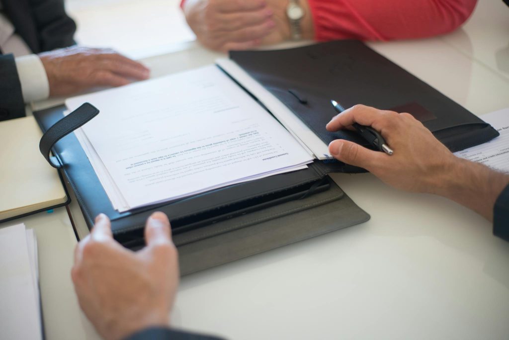 Two professionals discussing a contract with documents on a table, indoors.